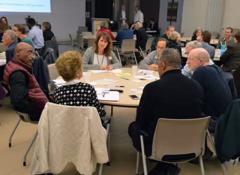 Community members sit around a round table in a planning meeting